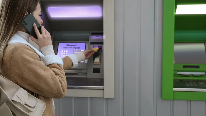 žena telefonuje u bankomatu