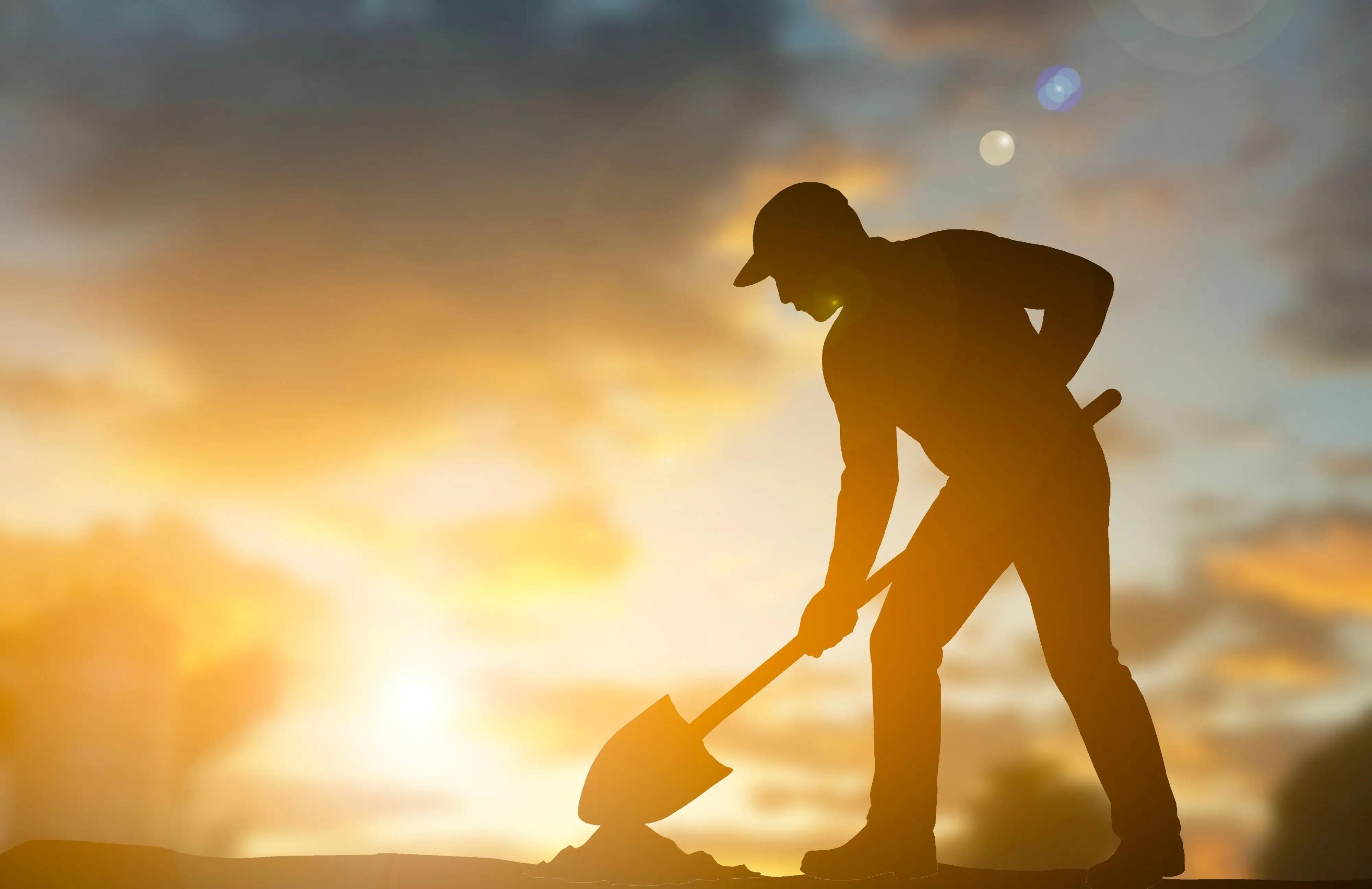 Muž při západu slunce s rýčem