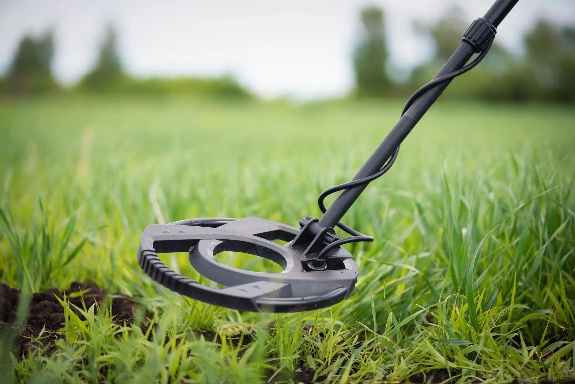 Detektor kovů hledá v trávě poklad