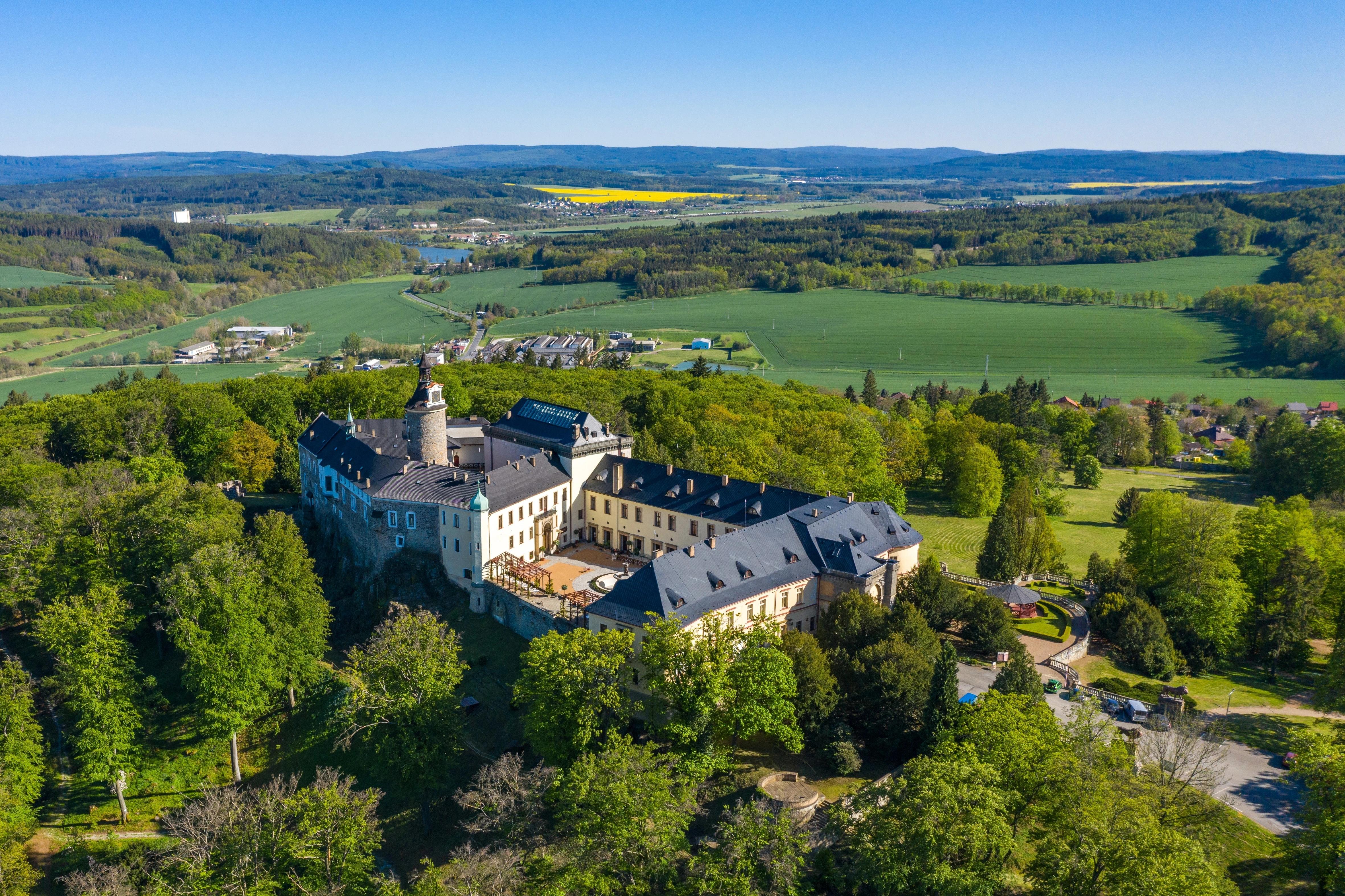 Rozlehlý zámek Zbiroh obklopený stromy ve slunečném dni