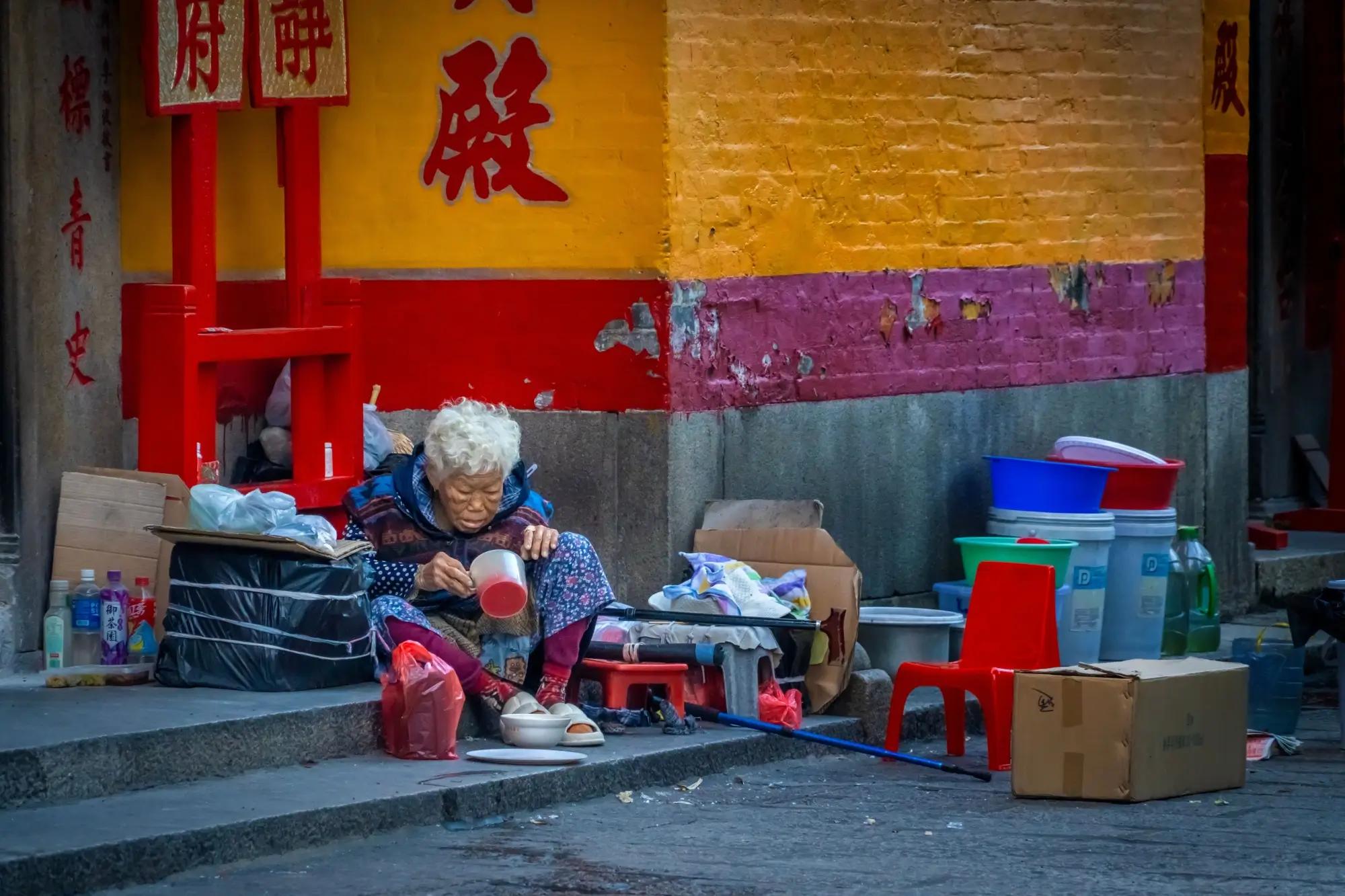 Žena bez domova sedí u dveří jednoho z čínských chrámů