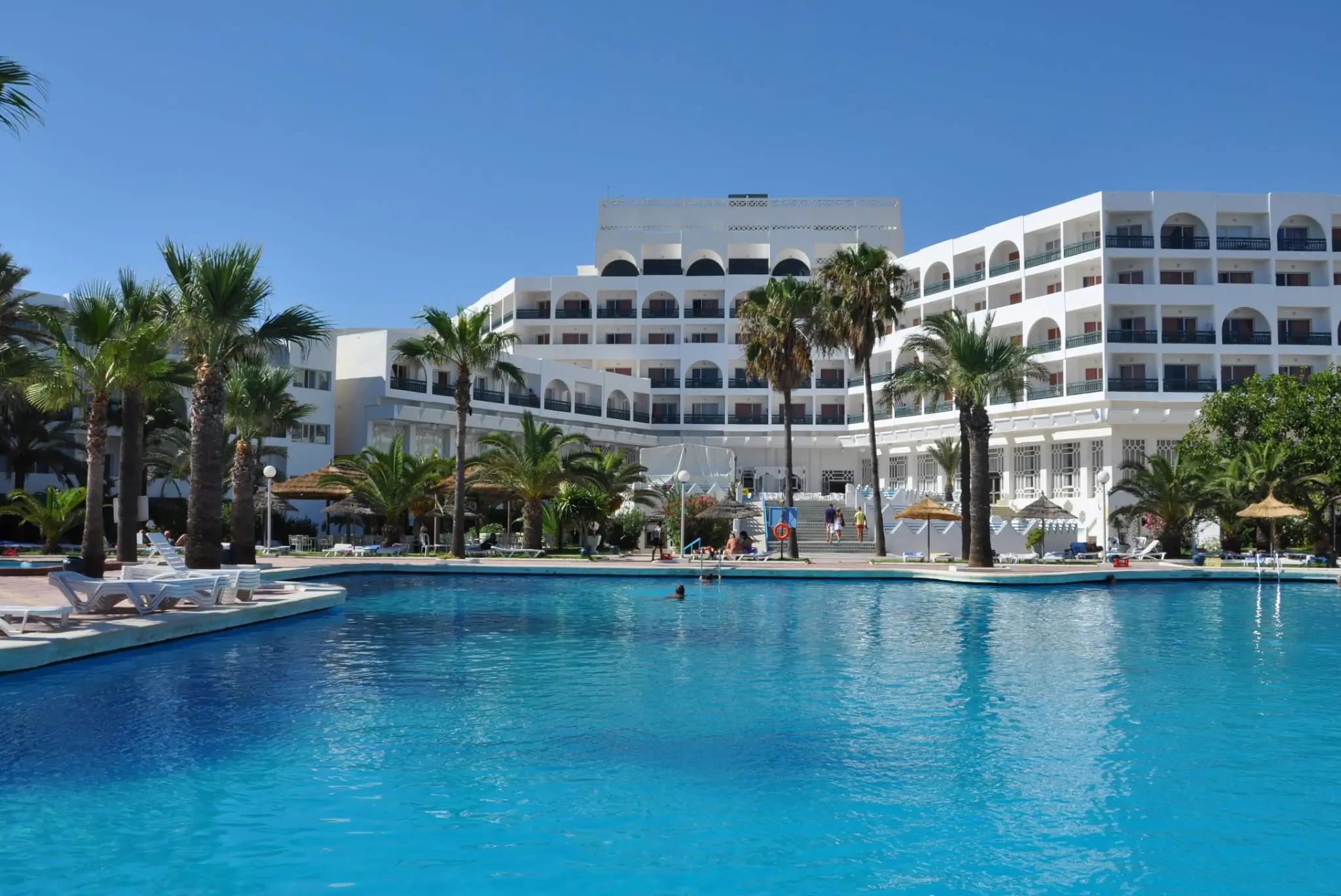 Pohled z bazénu na palmy a hotel.