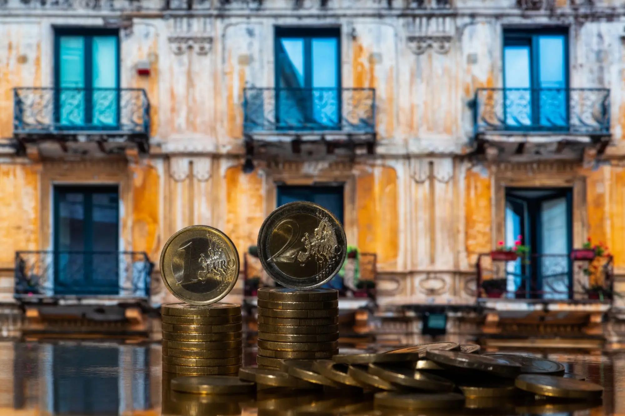 Historický dům s euro mincemi v popředí