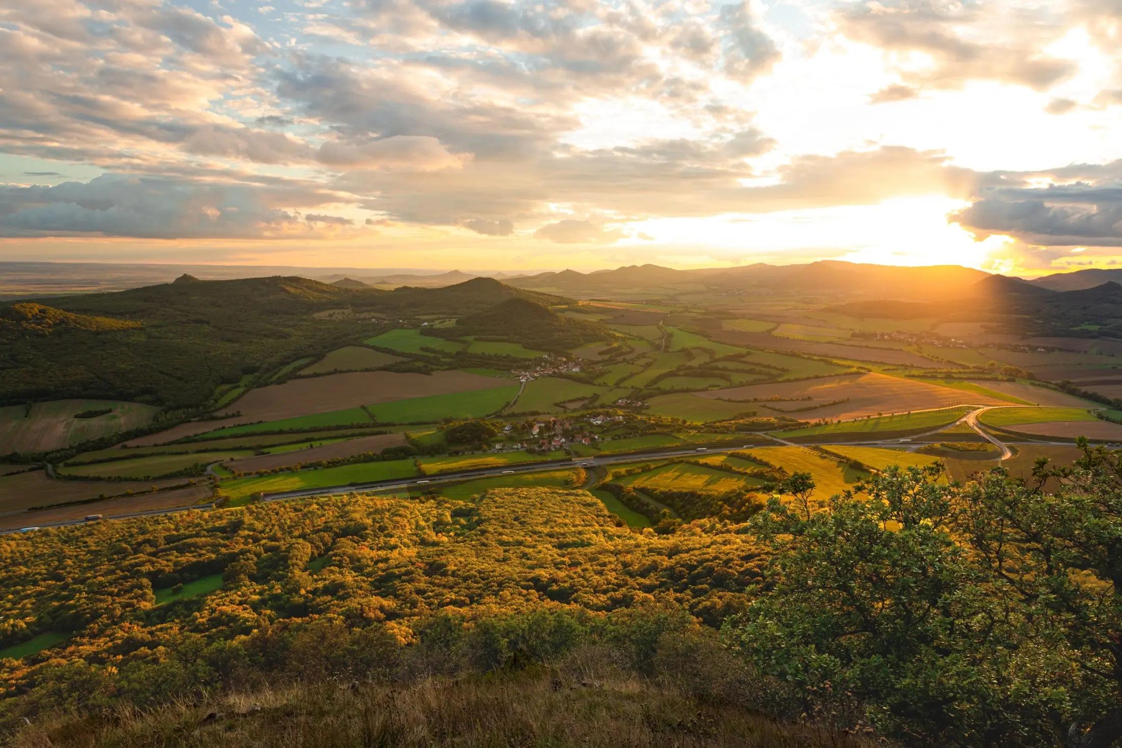 Panoramatický pohled na České středohoří. Zrovna zapadá Slunce, takže krajina je krásně osvícená.