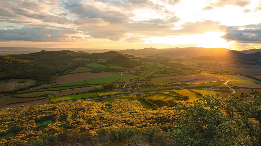 Panoramatický pohled na České středohoří. Zrovna zapadá Slunce, takže krajina je krásně osvícená.