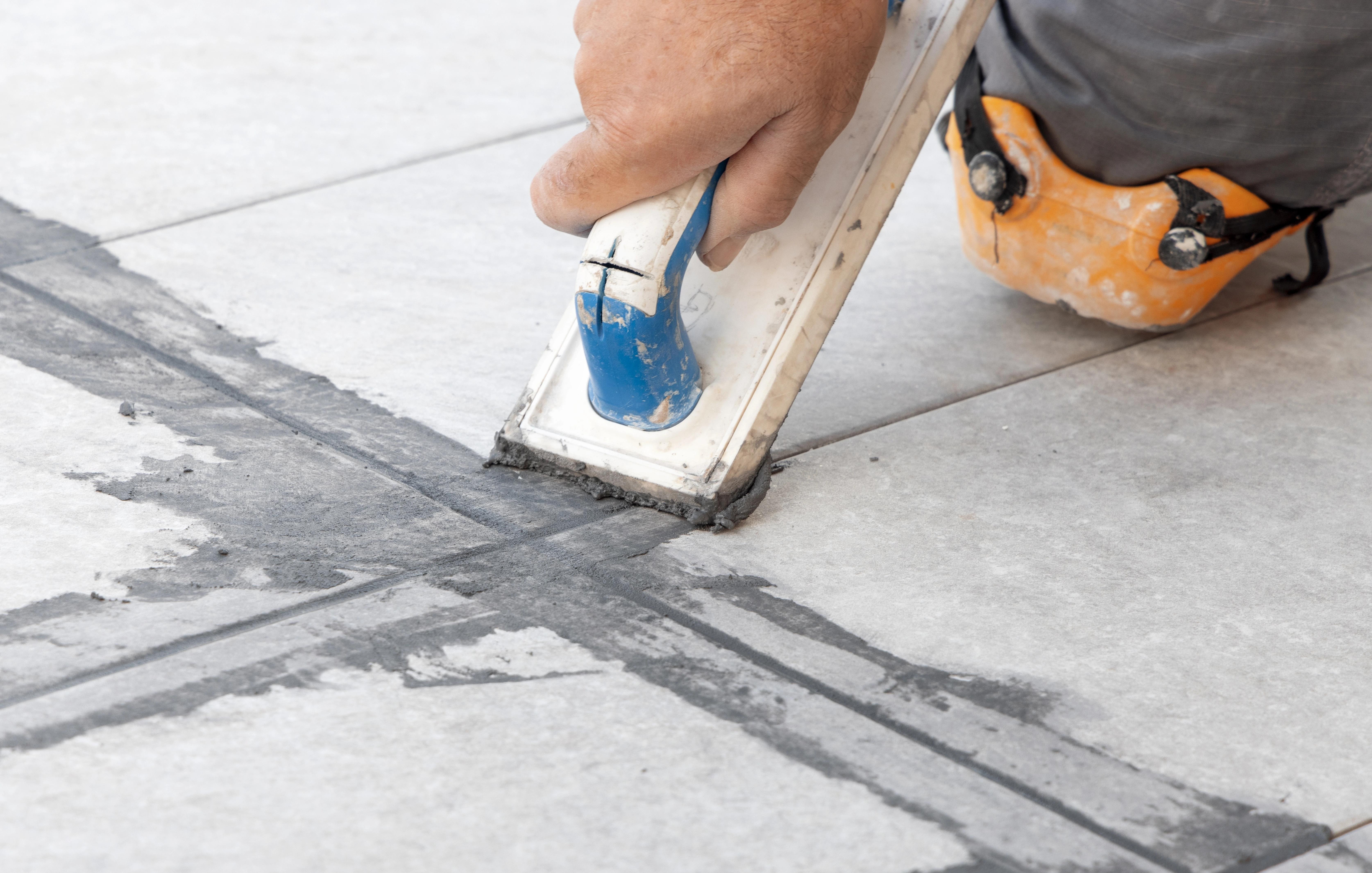 Řemeslník při spárování dlažby.