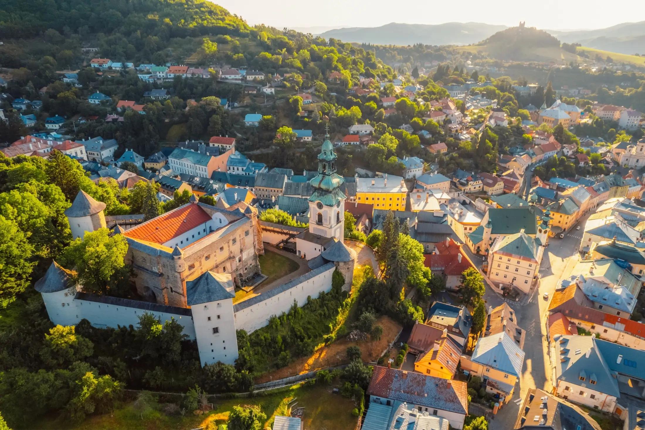 Letecký pohled na město Banská Štiavnica. Na levé straně jde vidět Starý zámek, poté ostatní domy města a zeleň okolí.