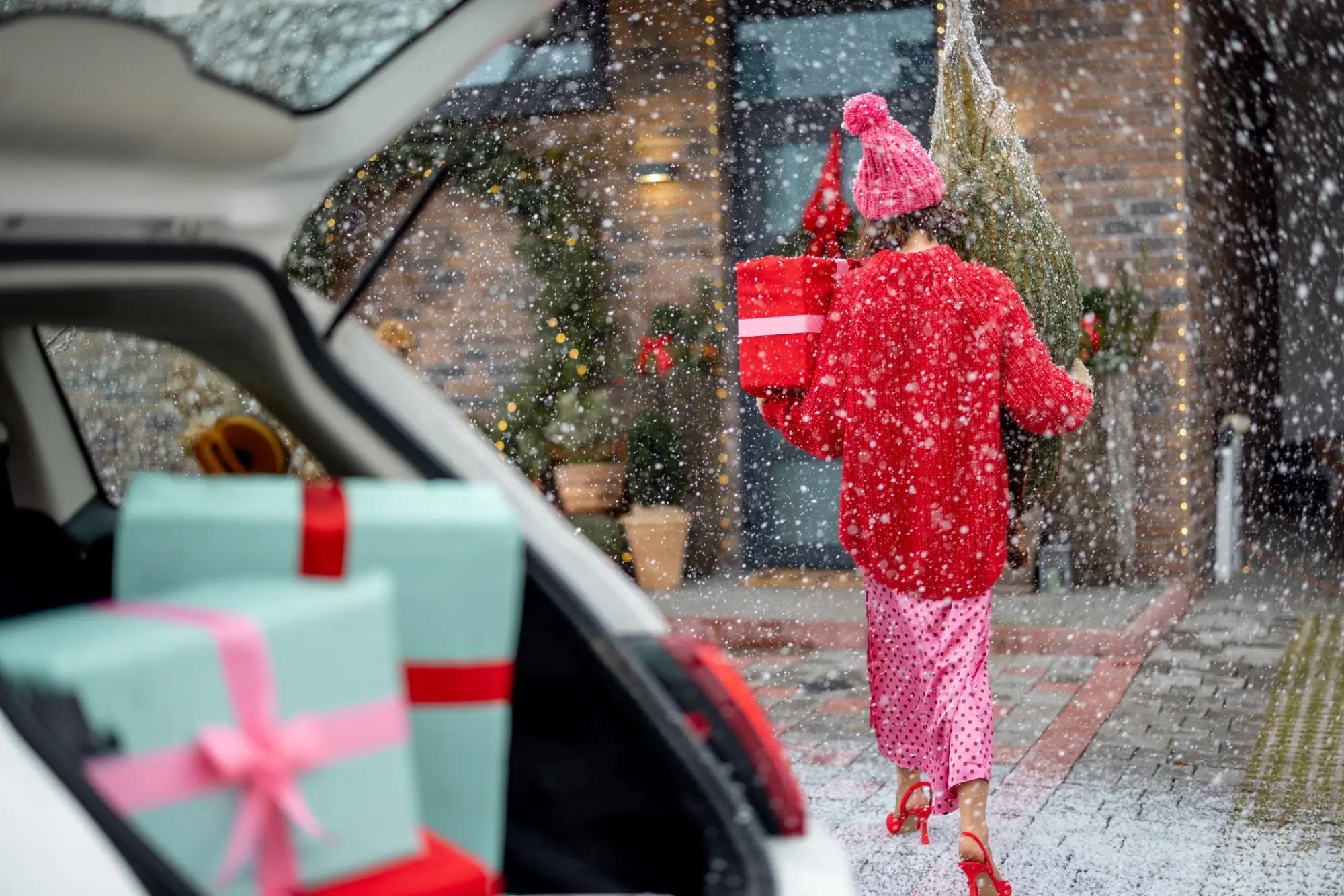 Žena nosící vánoční dárky z auta