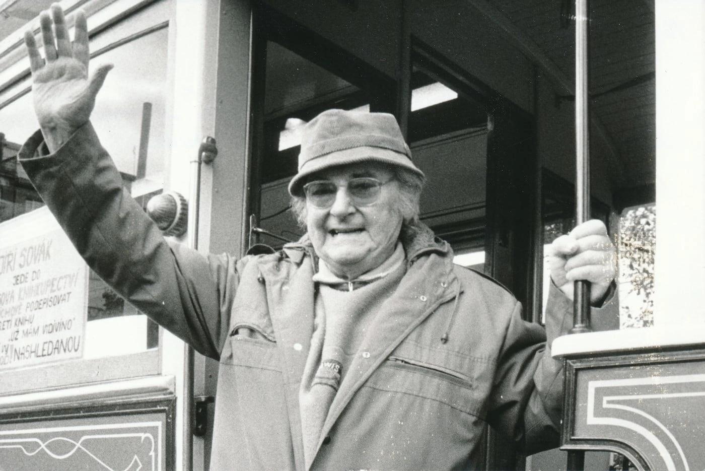 Usmívající a mávající Jiří Sovák v pozdějším věku, v kabátu a klobouku.