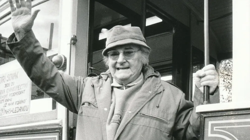 Usmívající a mávající Jiří Sovák v pozdějším věku, v kabátu a klobouku.