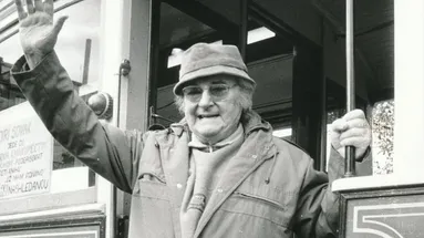 Usmívající a mávající Jiří Sovák v pozdějším věku, v kabátu a klobouku.