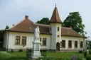 Světlý dům s červenou taškovou střechou, který se nachází v obci Chernelházadamonya. Stojí před ním jakási bílá socha.