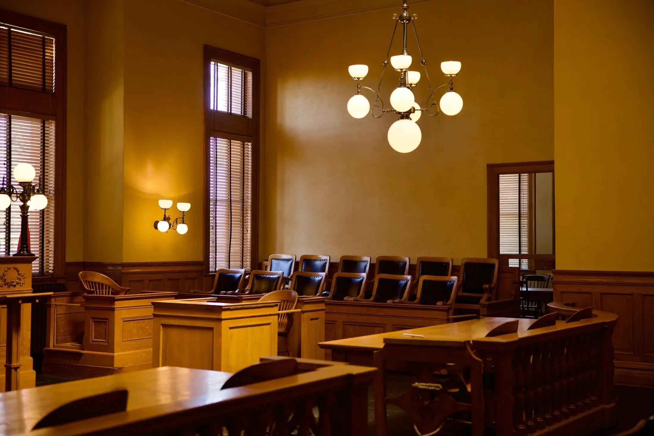 Soudní síň, má světle hnědé barvy, žlutá světla  dřevěný hnědý nábytek. Vidět jsou místa pro porotu a také stoly navrhovatele a odpůrce.