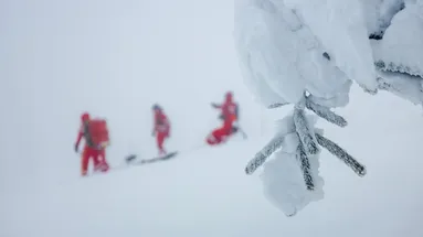 zasněžená scenérie v pozadí se záchranným týmem v červených kombinézách