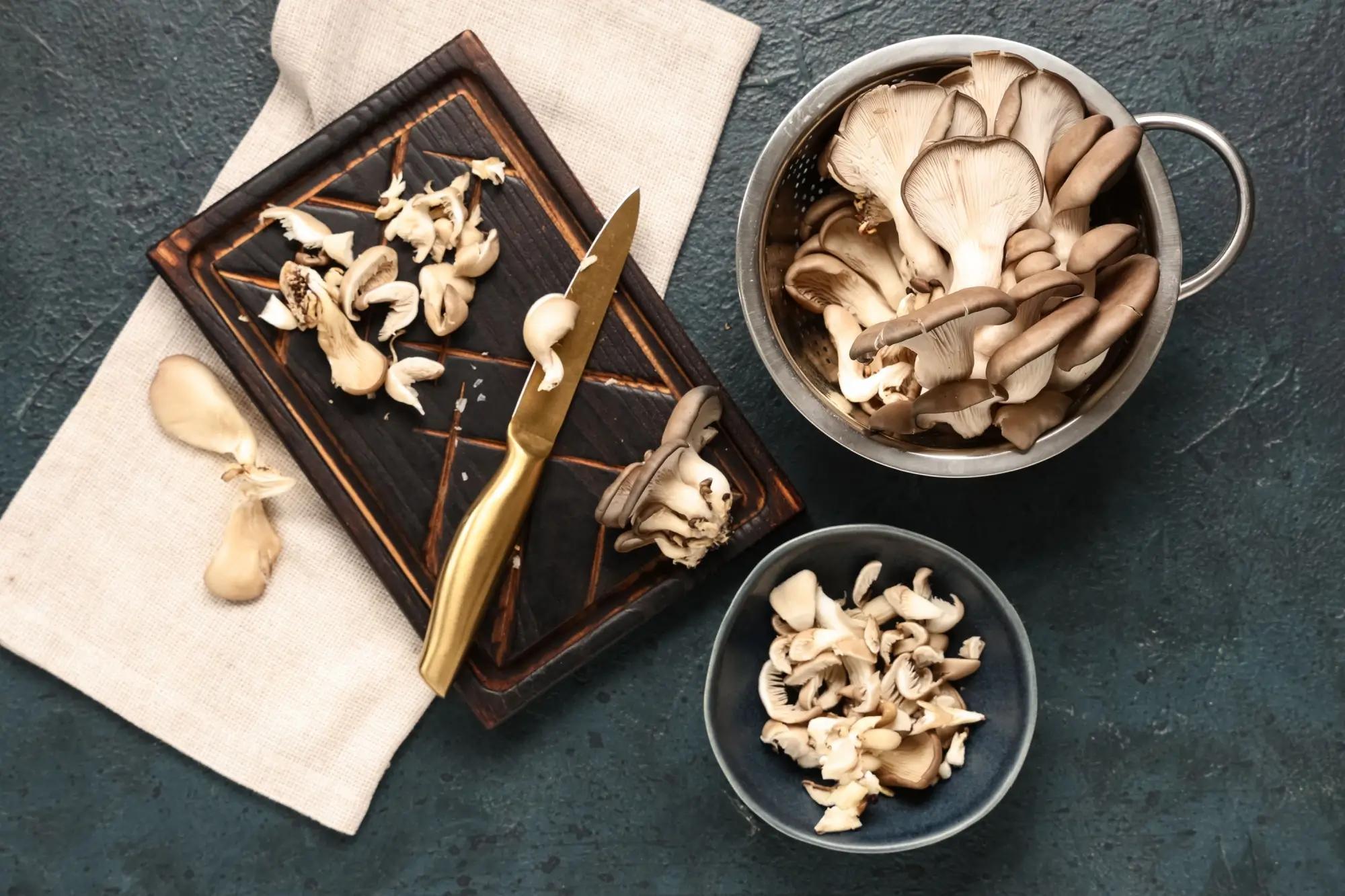 Rozkrájená hlíva ústřičná v hrnci, misce a na prkénku