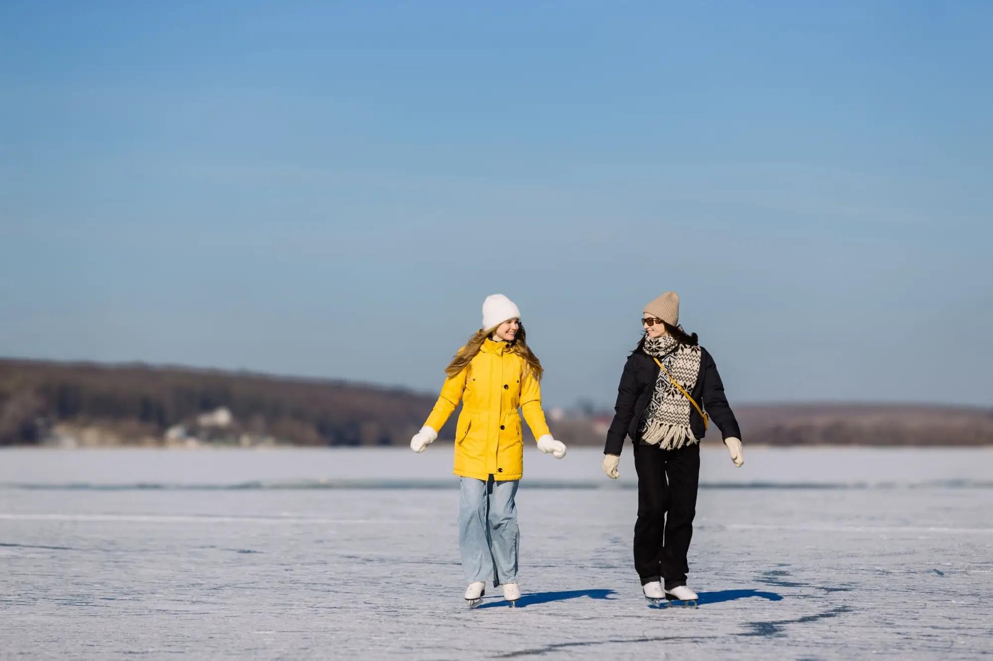 Dvě ženy bruslí na zamrzlém rybníku
