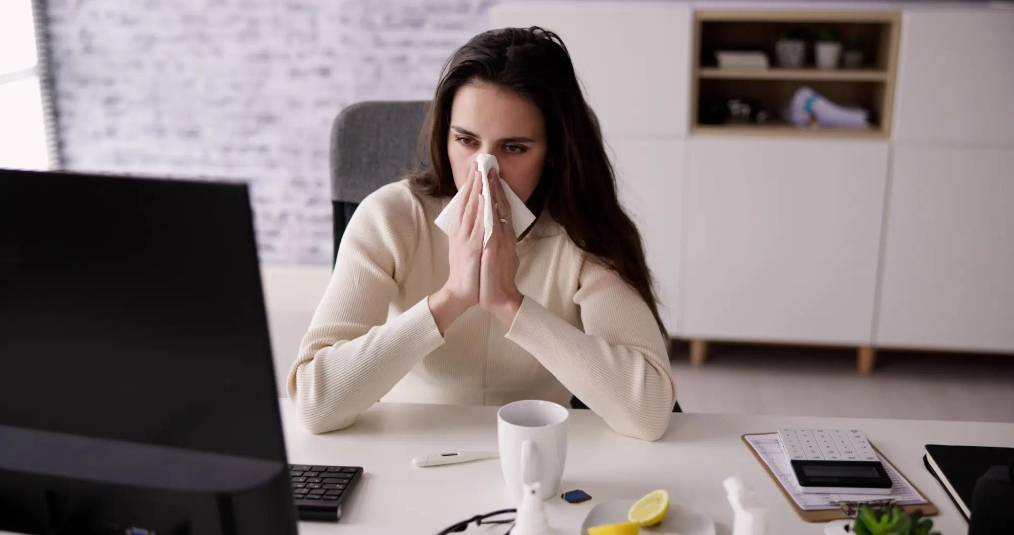 Smrkající zaměstnankyně, která sedí v kanceláři